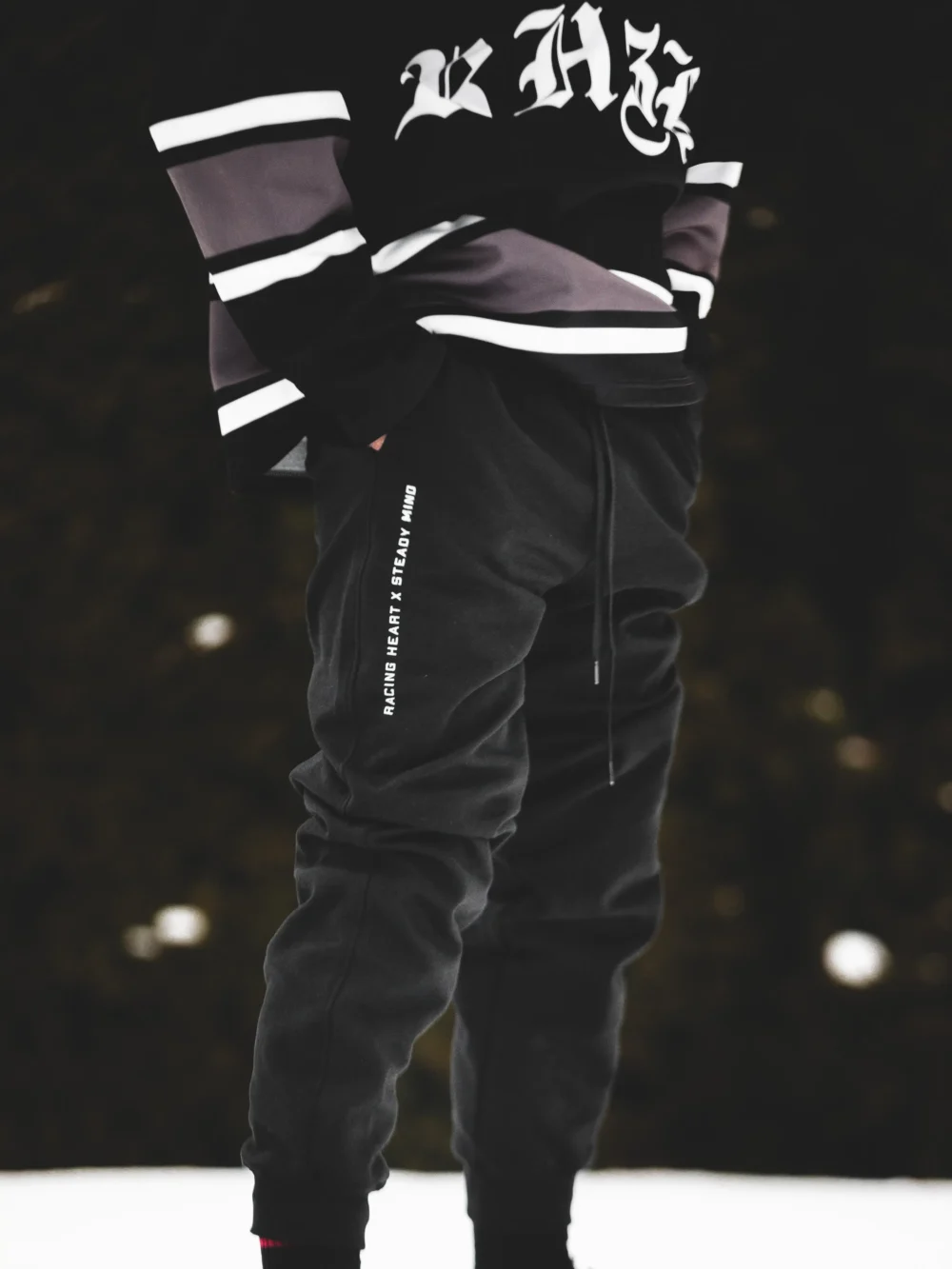 An athlete wearing the black RHSM Classic Fit Sweatpants during an outdoor calisthenics workout, with a close-up on the graphic.