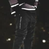 An athlete wearing the black RHSM Classic Fit Sweatpants during an outdoor calisthenics workout, with a close-up on the graphic.