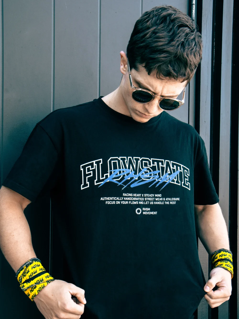 Outdoor close-up shot of a model wearing the black RHSM Flowstate graphic tee.