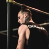 Elite calisthenics athlete Daniels Laizans on stage at a competition, wearing the black RHSM Godmode Tank Top.