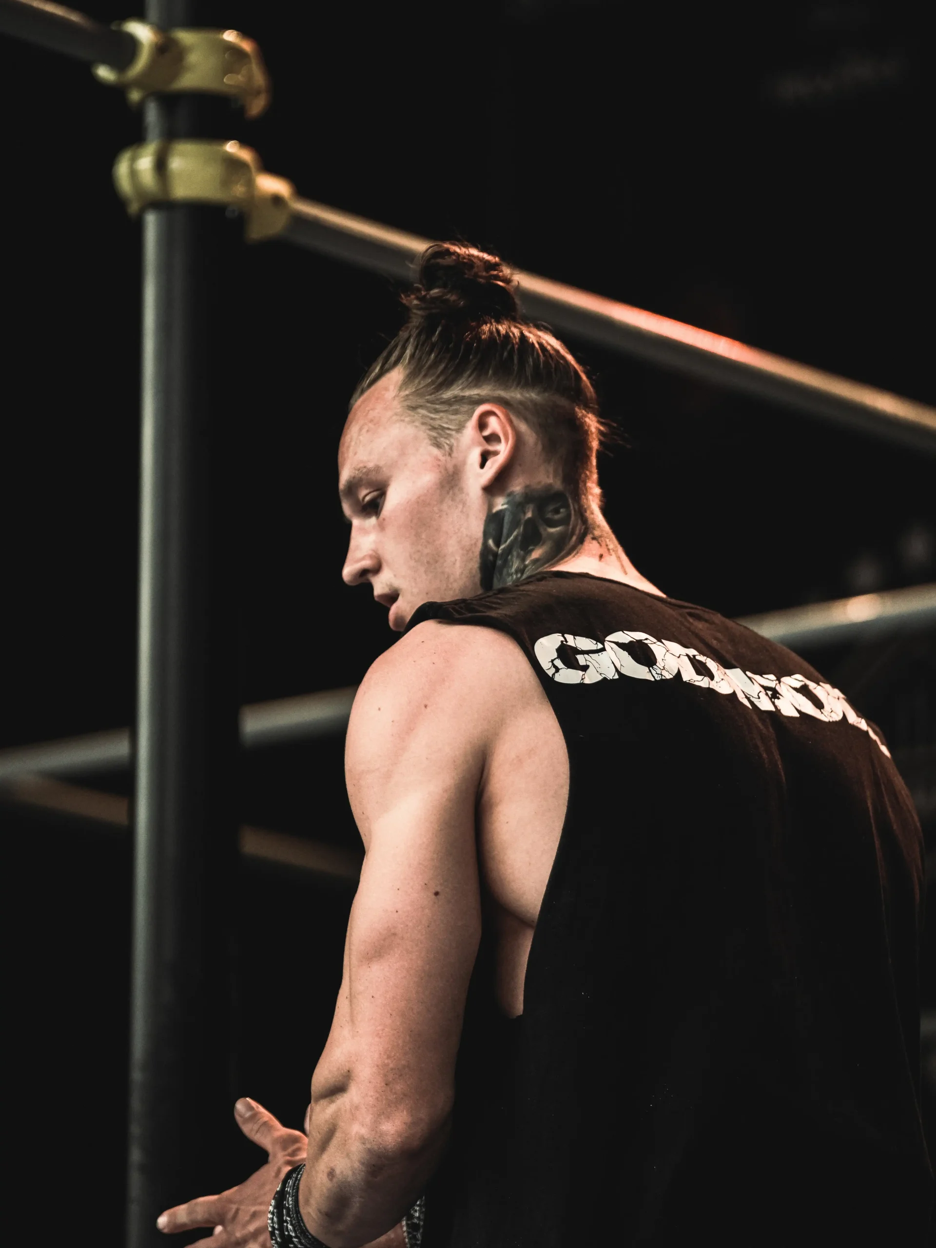 Elite calisthenics athlete Daniels Laizans on stage at a competition, wearing the black RHSM Godmode Tank Top.