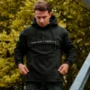 Model showcasing the spacious front kangaroo pocket of the black RHSM MVMT Hoodie.