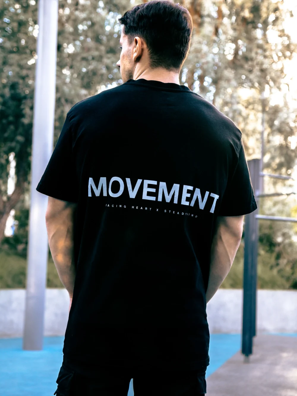 An athlete wearing the oversized black RHSM Movement Tee outside, showing the minimalist graphic on the back.