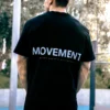 An athlete wearing the oversized black RHSM Movement Tee outside, showing the minimalist graphic on the back.