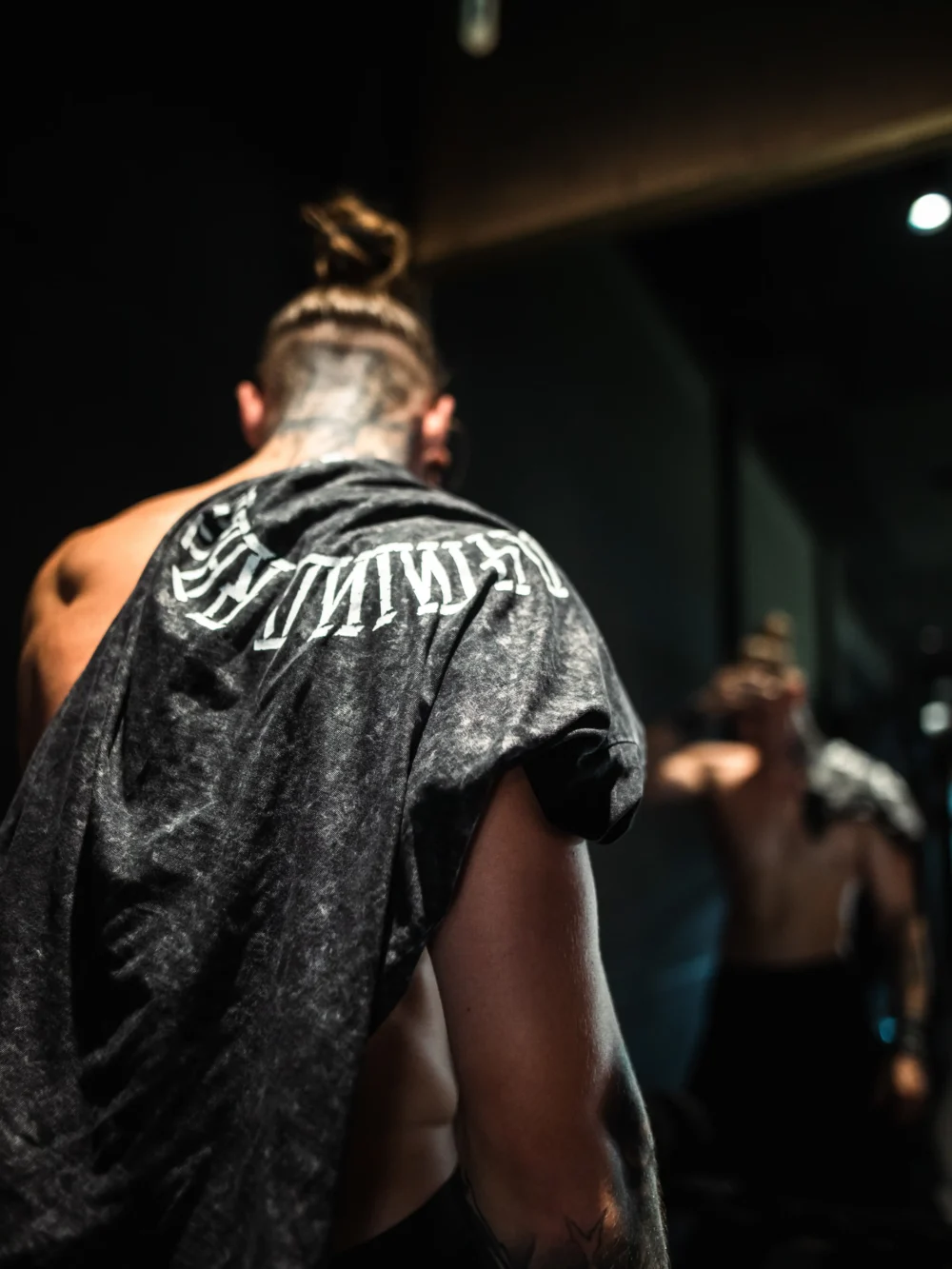 A stylistic back view of an athlete with the RHSM Acid Wash Tee on his shoulder after a calisthenics workout.