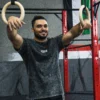A model wearing the RHSM Acid Wash Tee in a gym setting near a pair of gymnastic rings.