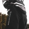 A full view of a model wearing the black RHSM Classic Fit Sweatpants in an outdoor setting, showcasing their versatile streetwear and training style.