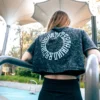 An athlete wearing the RHSM Acid Wash Crop-Top at an outdoor calisthenics park, showing the back graphic.