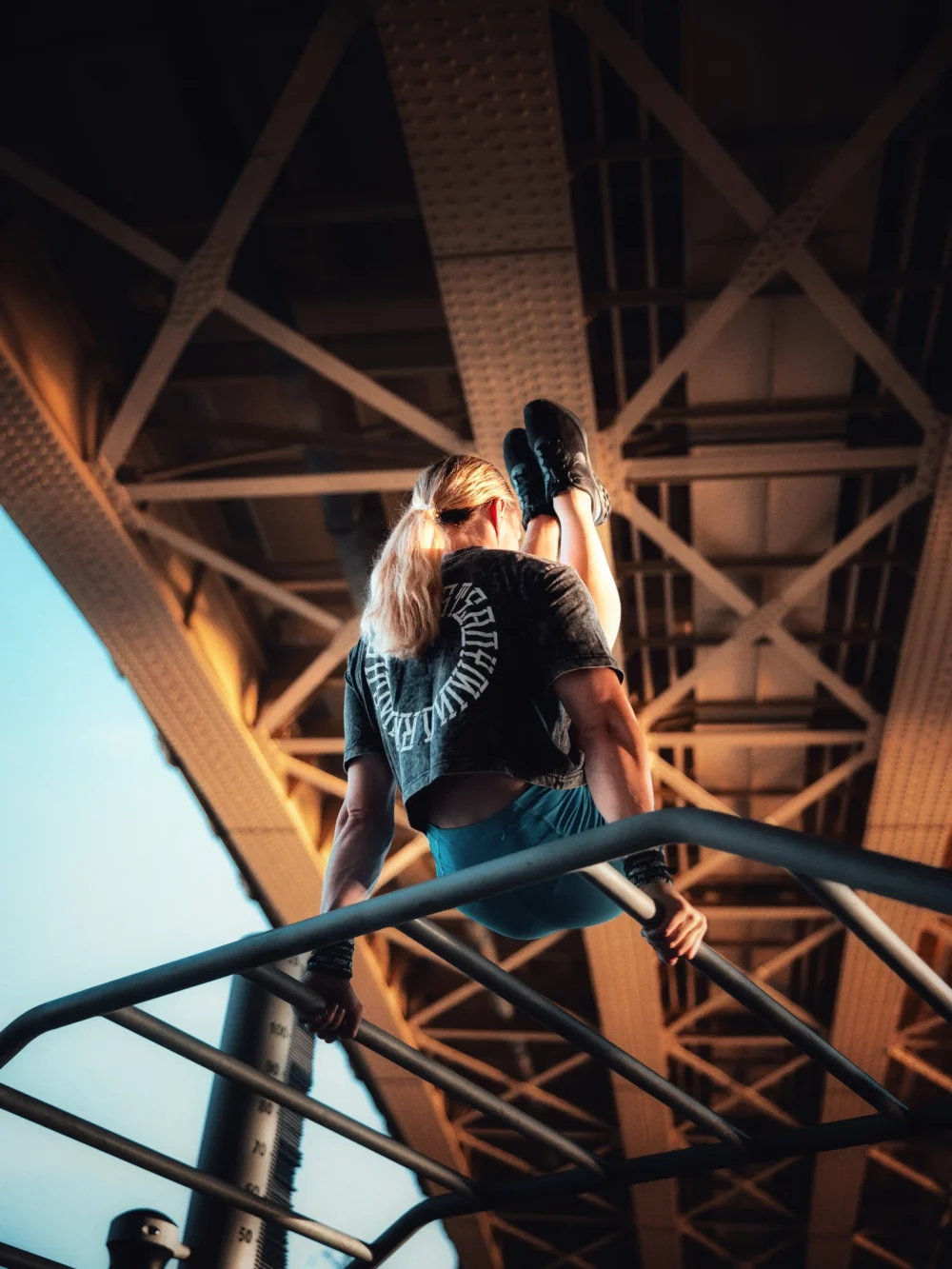 Back view of an athlete doing an l-sit in an urban setting, wearing the stylish RHSM Acid Wash Crop-Top.