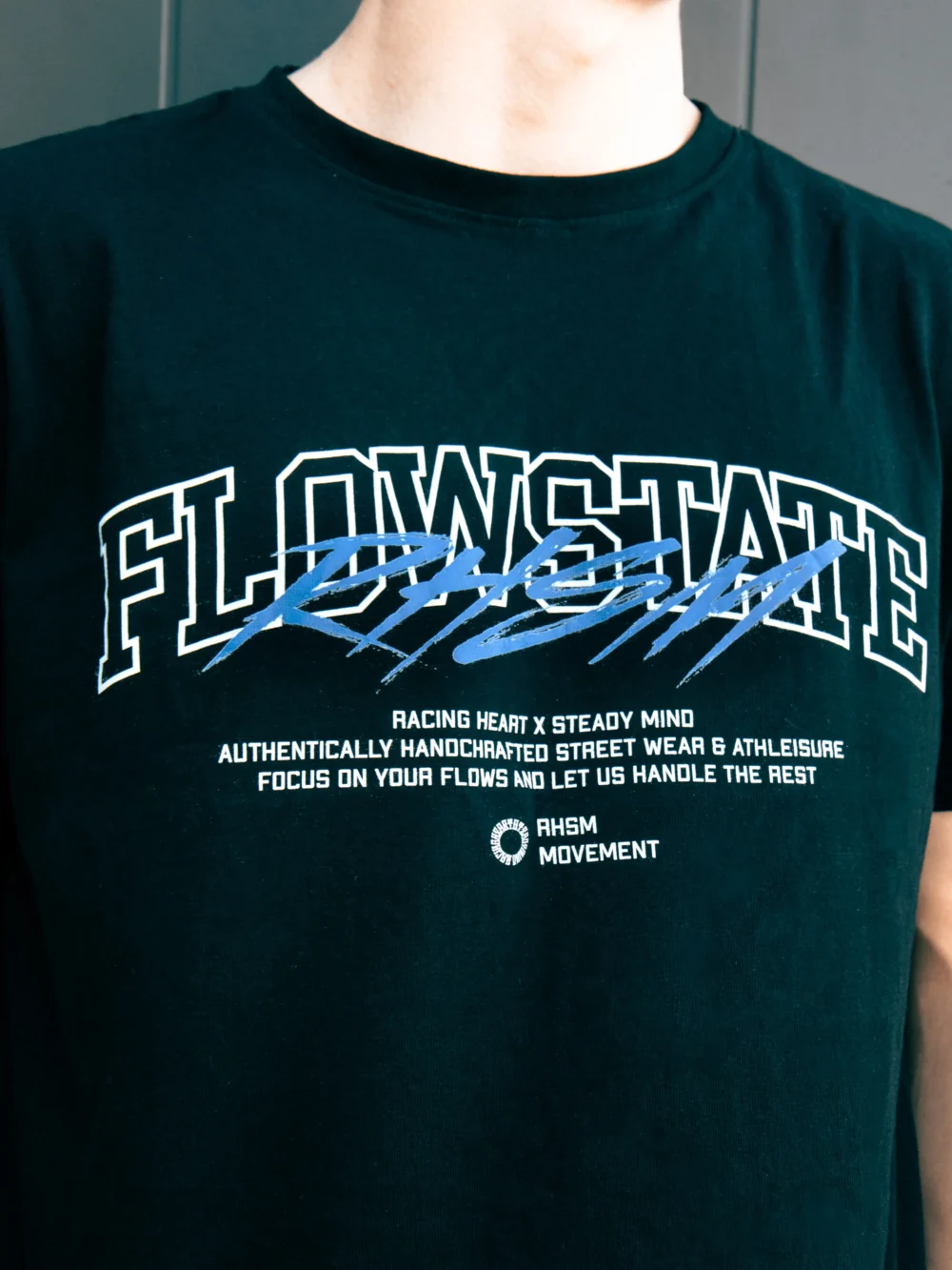 Detailed close-up of the screen-printed graphic and 100% premium cotton fabric of the black RHSM Flowstate Tee.