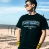 Model wearing the oversized black RHSM Flowstate Tee at the beach, showcasing its streetwear style.
