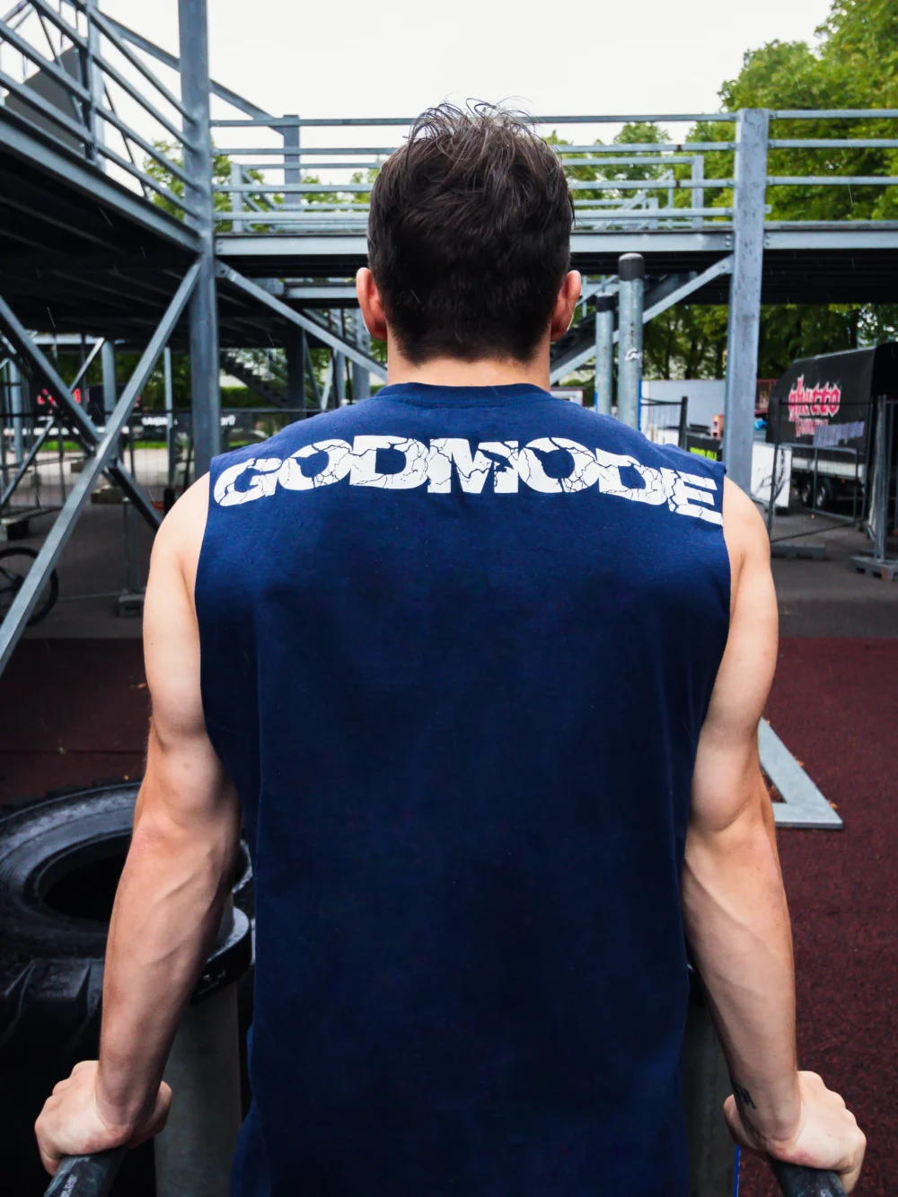 An athlete performing dips at an outdoor park while wearing the blue RHSM Godmode Tank Top.
