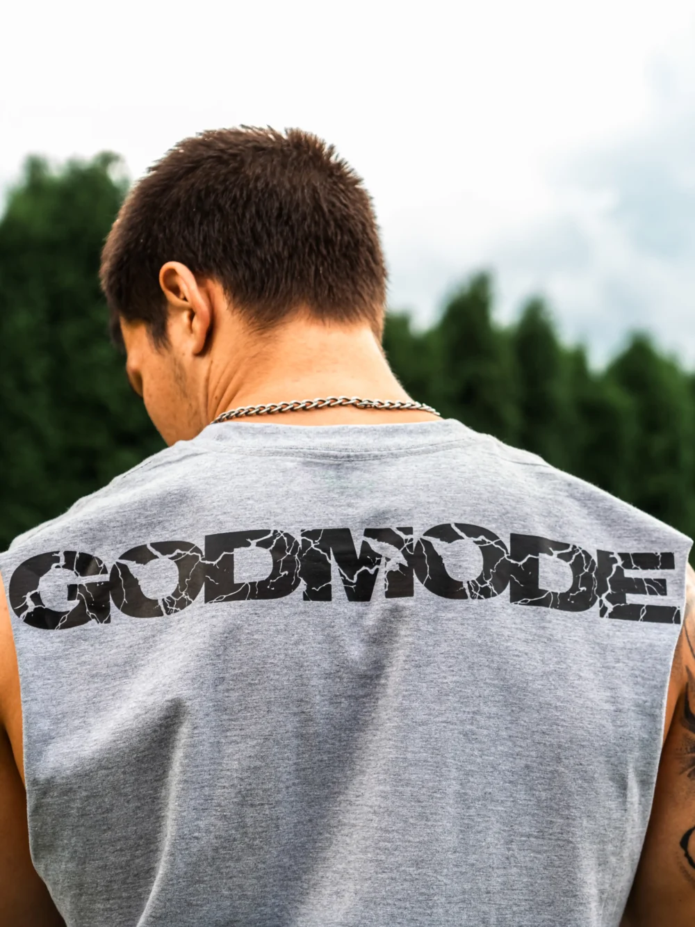 Back view of an athlete wearing the gray RHSM Godmode Tank Top during an outdoor street workout.