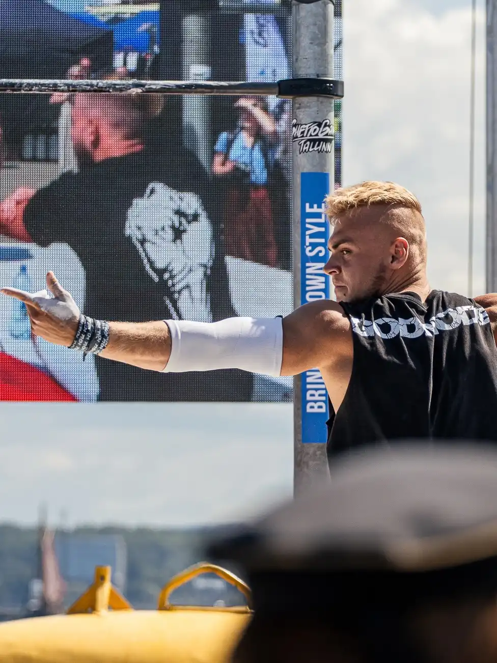 A calisthenics competitor wearing the RHSM Godmode Tank Top on stage during a competition.
