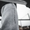 An outdoor close-up of the "Racing Heart X Steady Mind" graphic on the gray RHSM Classic Fit Sweatpants, worn by a model.