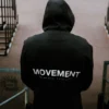 An athlete wearing the black RHSM MVMT Hoodie in an urban setting, highlighting its streetwear aesthetic.