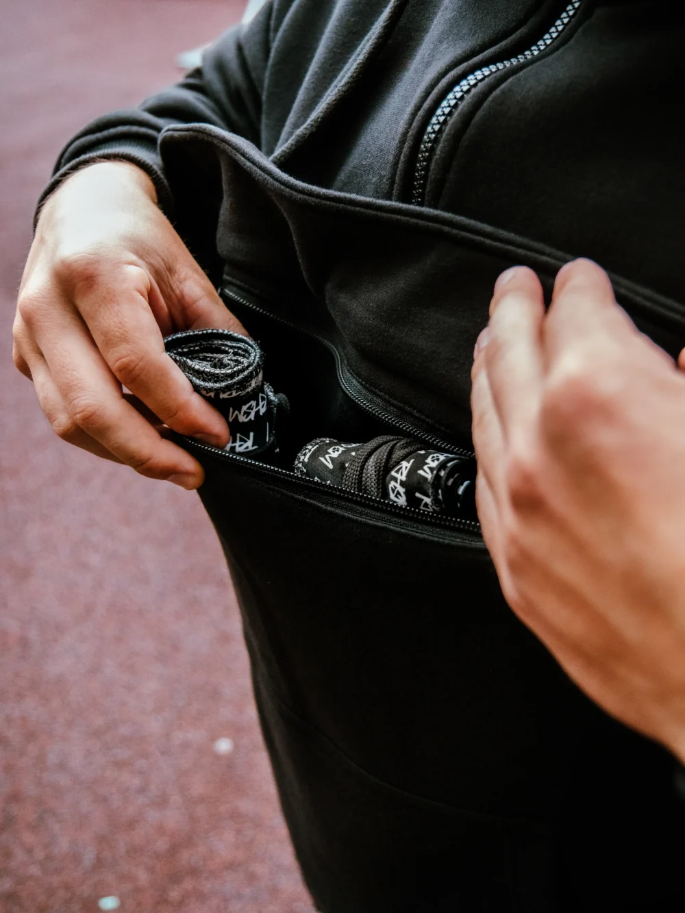 Close-up of the front pouch on the RHSM MVMT Hoodie being used to carry everyday essentials like wrist wraps.