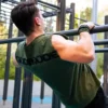 An athlete performing Australian pull-ups while wearing the khaki RHSM Godmode Tank Top, showing the back graphic in action.