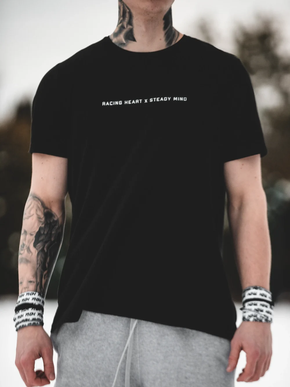 A full front view of a model wearing the black RHSM Classic Fit Tee in an outdoor setting.