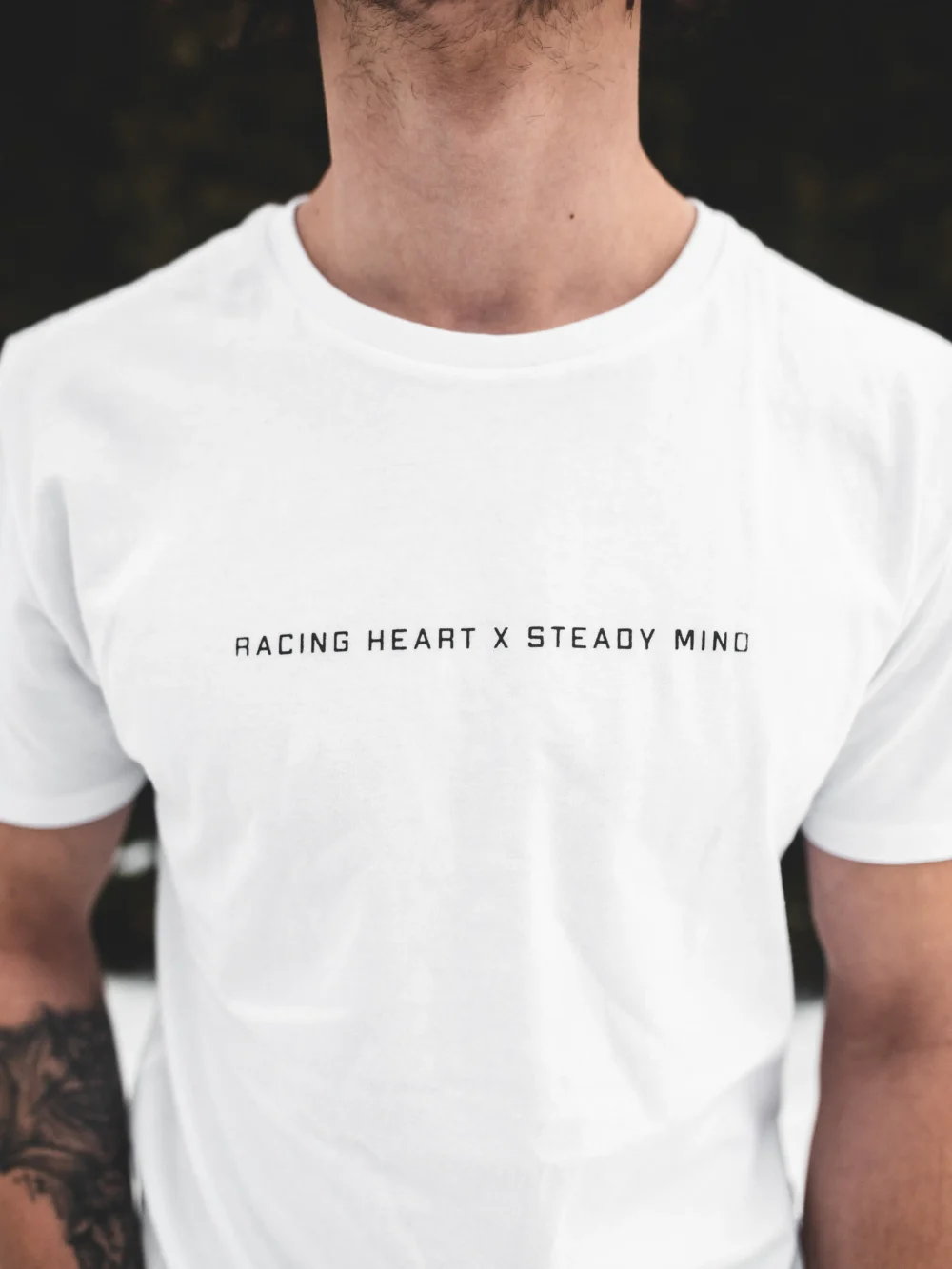 An outdoor close-up shot of a model wearing the white RHSM Classic Fit Tee.