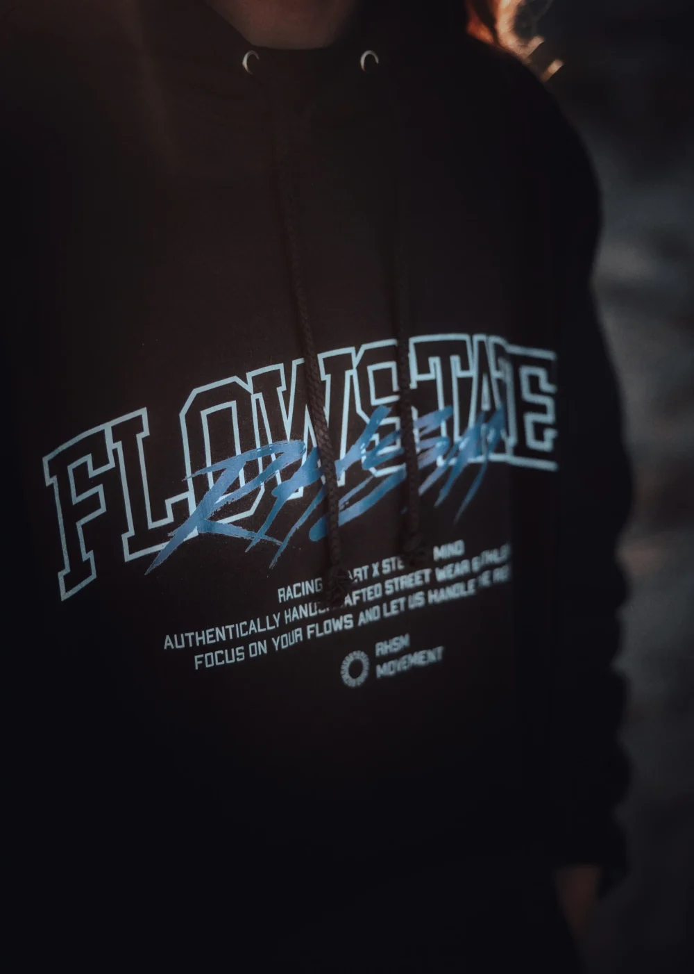Close-up of the RHSM Flowstate Hoodie's durable fabric being worn in an outdoor calisthenics park.