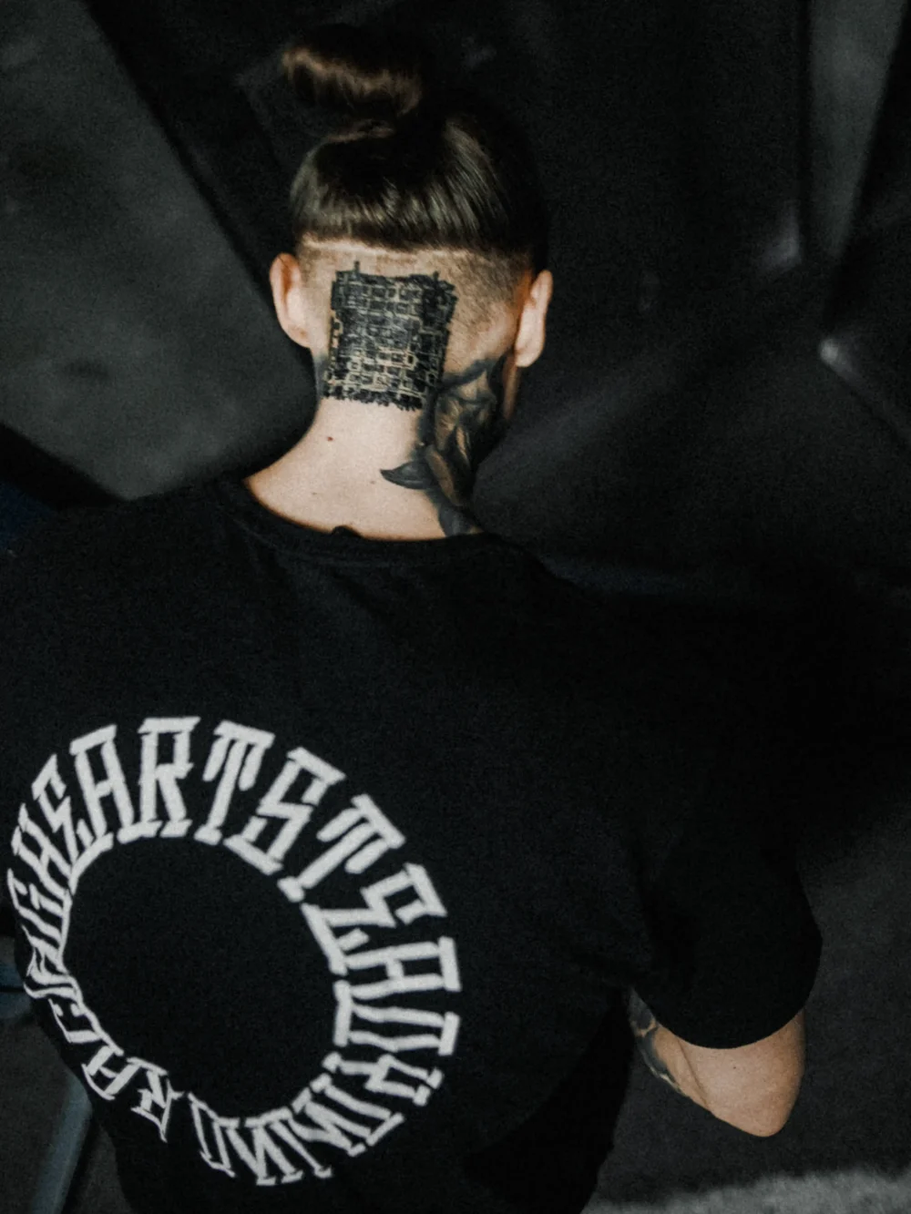 Top-down back view of calisthenics athlete Daniels Laizans showcasing the "Racing Heart Steady Mind" graphic on the RHSM Long Fit Tee V2.