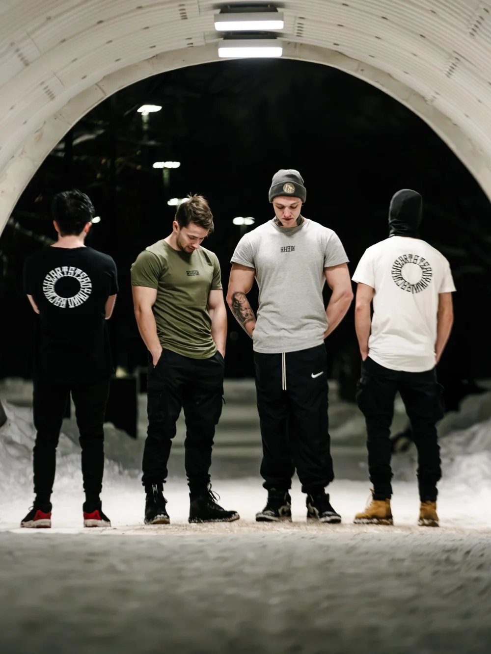Athletes Pauls Jemeljanovs and Daniels Laizans wearing the RHSM Long Fit Tee V2 collection, showcasing all colorways including black, white, gray, and khaki.