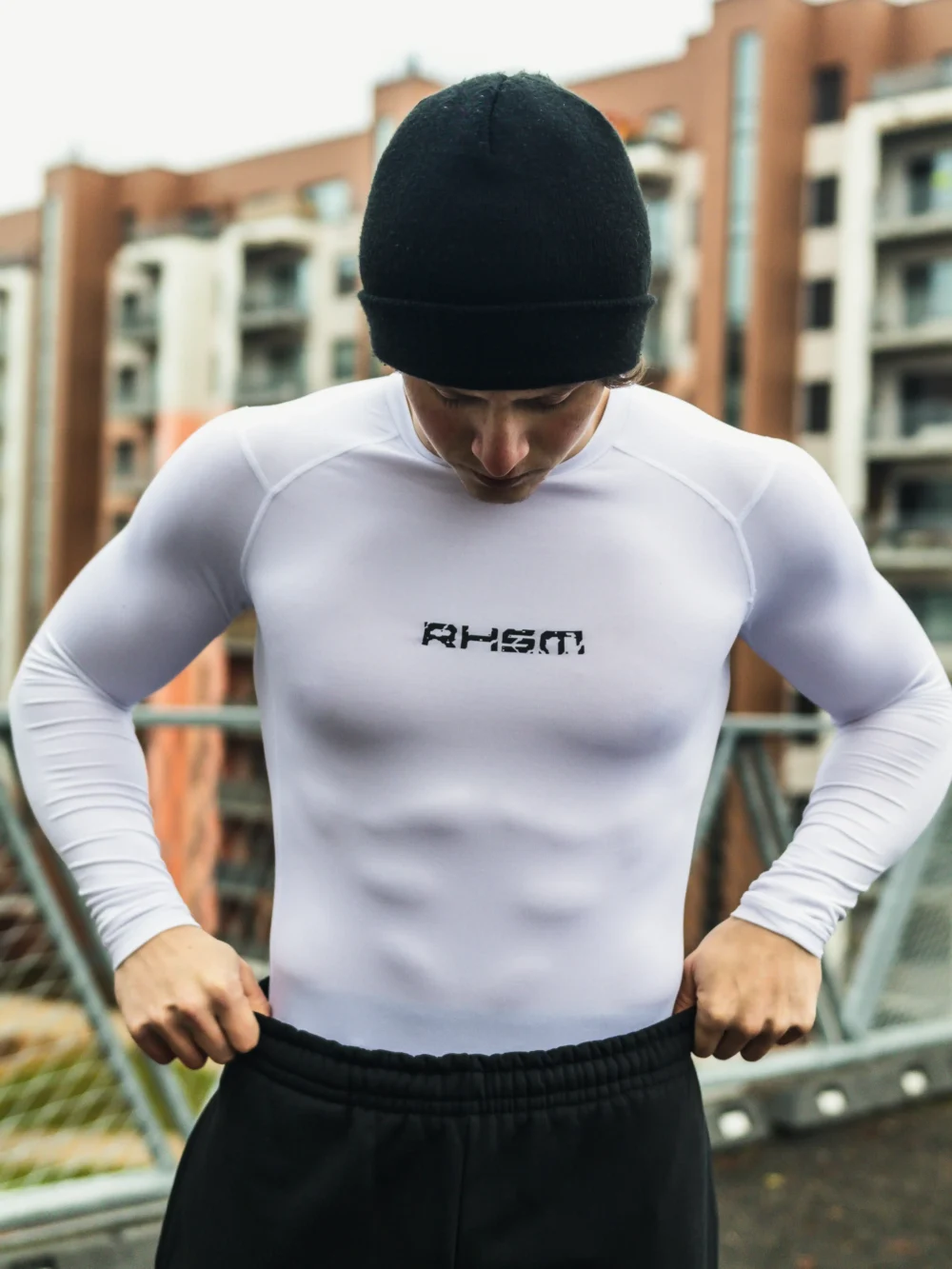 Front view of an athlete wearing the white RHSM Compression Shirt in an outdoor training setting.