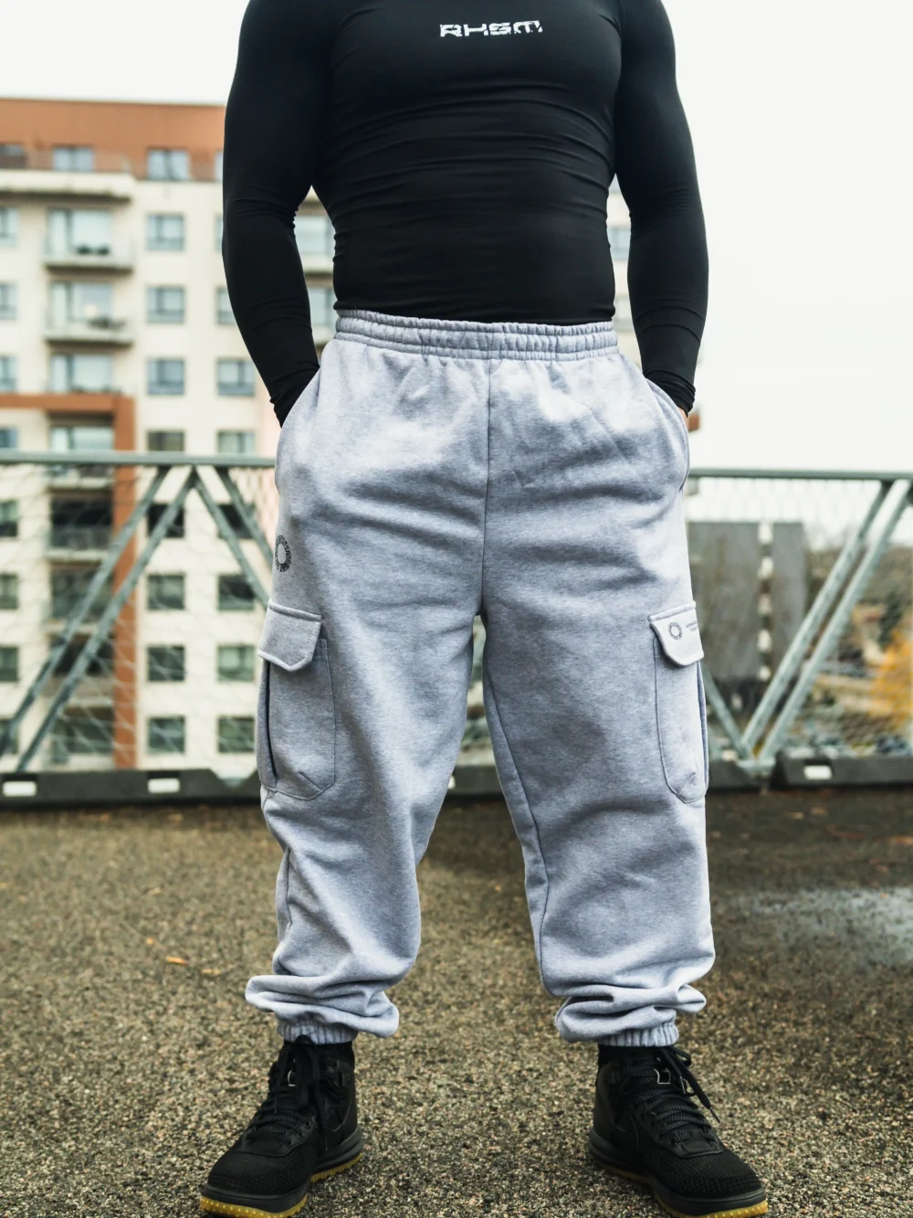 Full front view of a model wearing the gray RHSM Cargo Sweatpants in an outdoor setting.