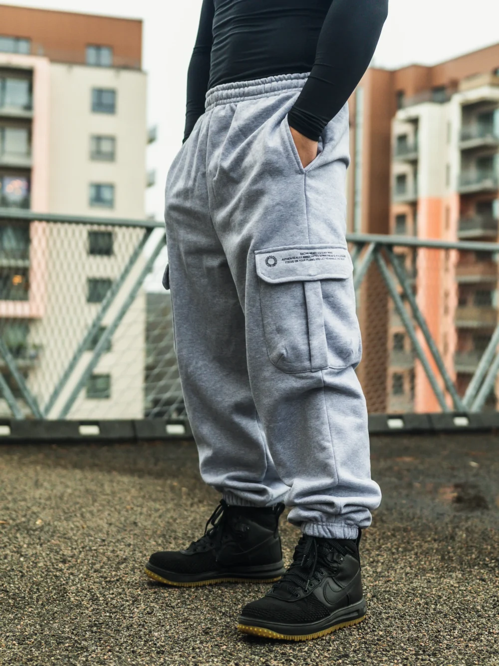 A side view of a model showing the secure latch detail on the cargo pocket of the gray RHSM Sweatpants.