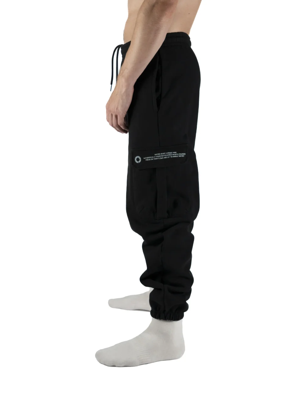 Side view of a model wearing the black RHSM Cargo Sweatpants, showcasing the functional side cargo pocket.