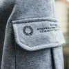 An outdoor close-up of the secure latch on the side cargo pocket of the gray RHSM Sweatpants.