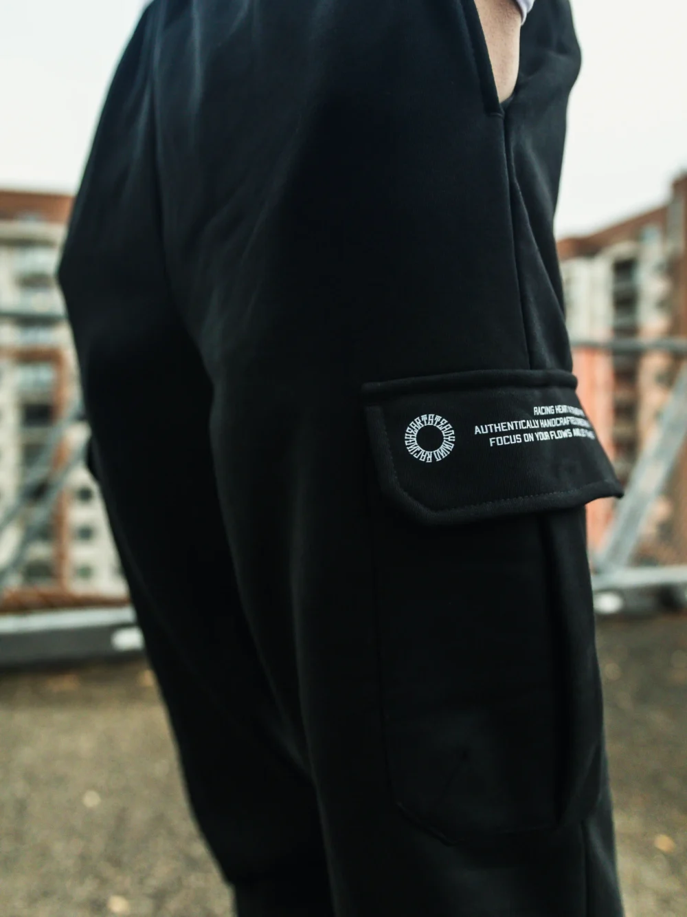 A detailed close-up of the secure latch design on the side cargo pocket of the black RHSM Cargo Sweatpants.