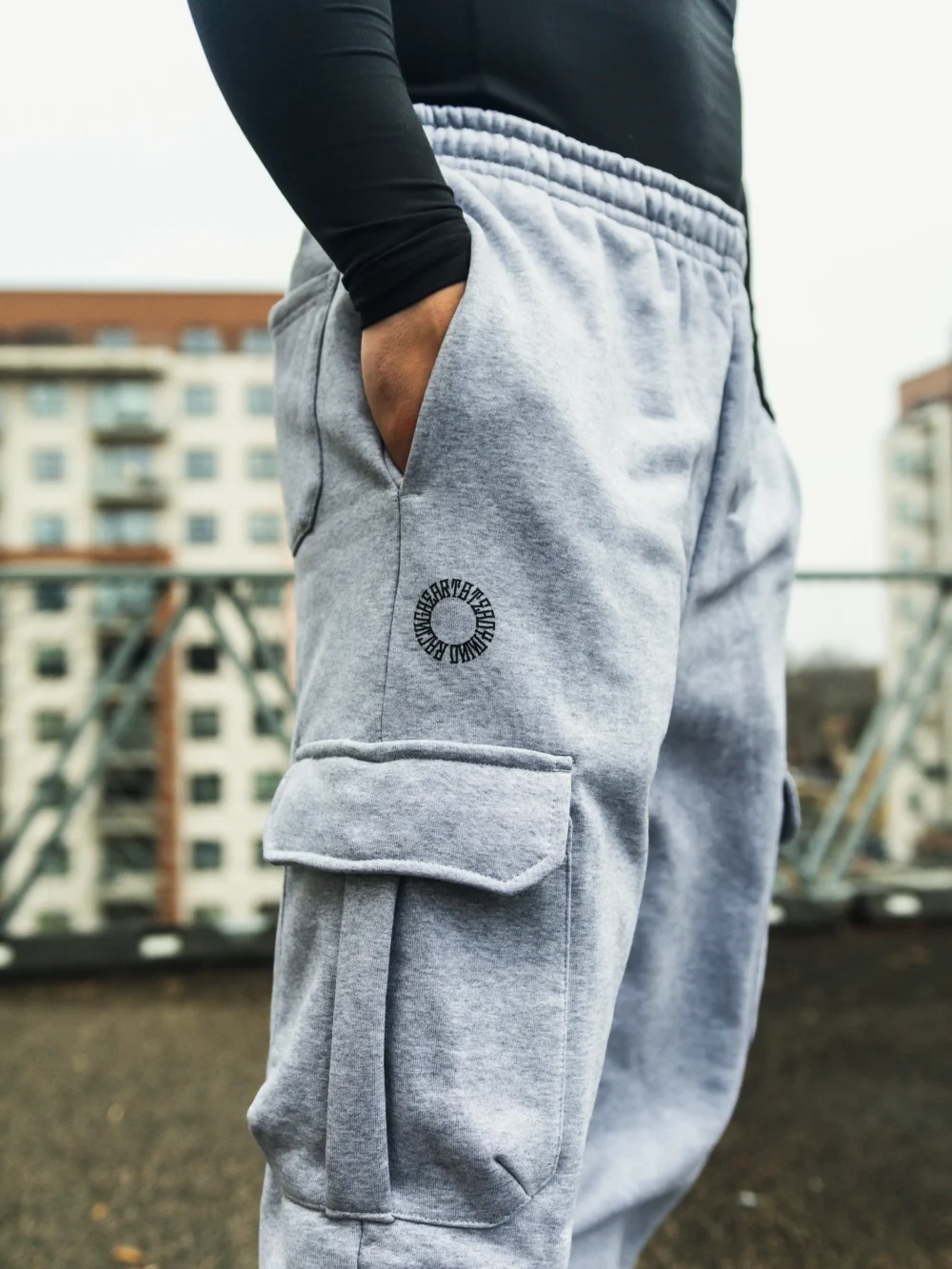 A full side profile of a model wearing the gray RHSM Cargo Sweatpants outdoors, showcasing the modern silhouette.