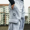 A full side profile of a model wearing the gray RHSM Cargo Sweatpants outdoors, showcasing the modern silhouette.