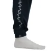 A detailed close-up of the sewn-in RHSM label on the right leg cuff of the navy GODMODE trackpants.