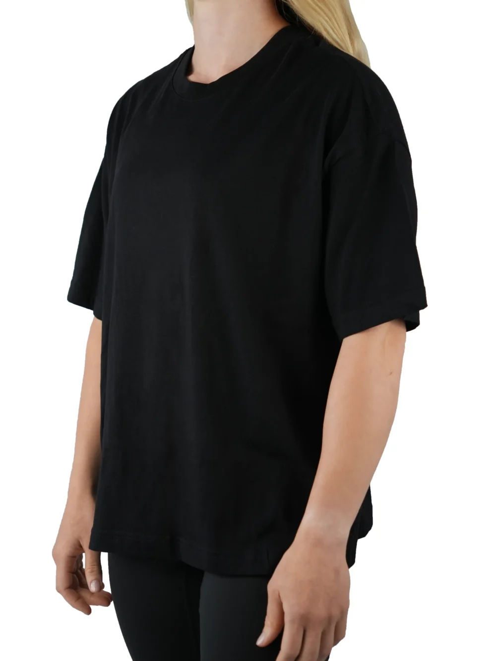A female model wearing the black oversized boxy tee from the front, demonstrating its modern boxy silhouette and dropped shoulder fit.