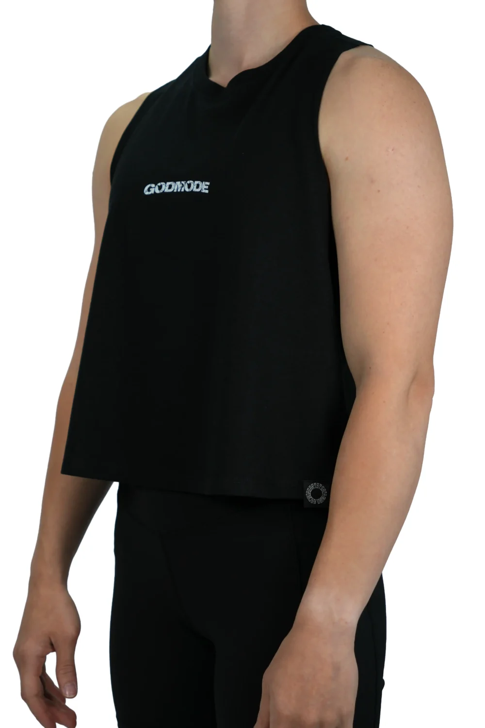 Model wearing the black "GODMODE" cropped tank (front view), demonstrating the flattering fit and raw arm holes of this women's workout gear.