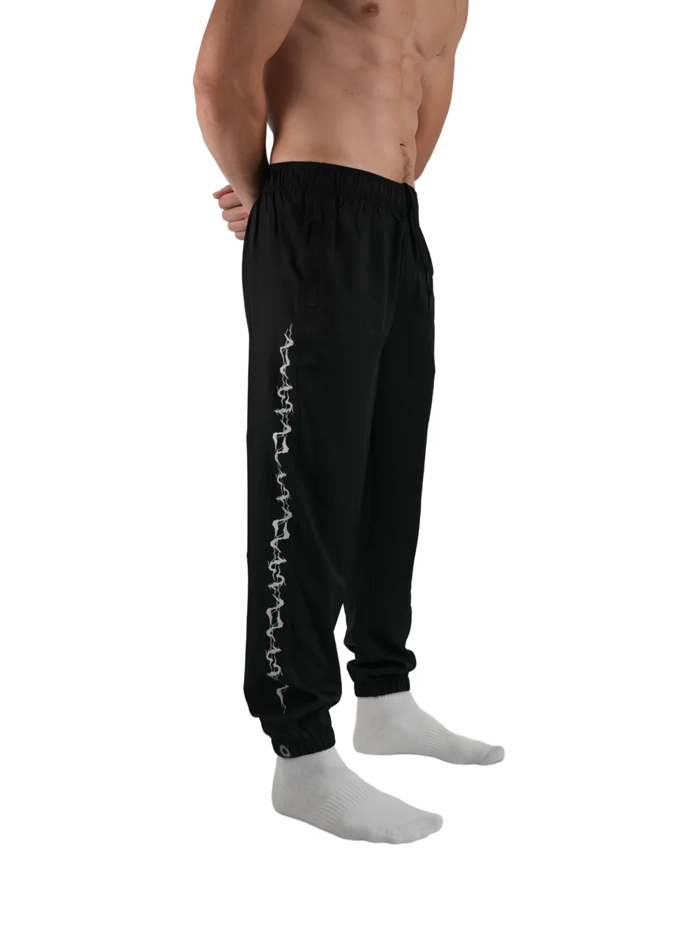Model wearing the black GODMODE trackpants (front view), highlighting the modern athletic fit of this essential workout gear.