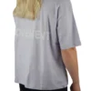 Back view of a female model wearing the lilac oversized boxy tee, showcasing the black "Movement" graphic and the tee's wide, loose fit.