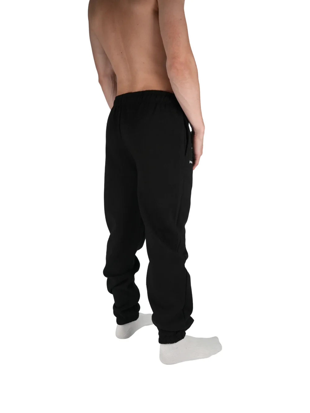 Model wearing the black "[RHXSM]" sweatpants, highlighting the modern relaxed fit and soft material of this essential workout gear.