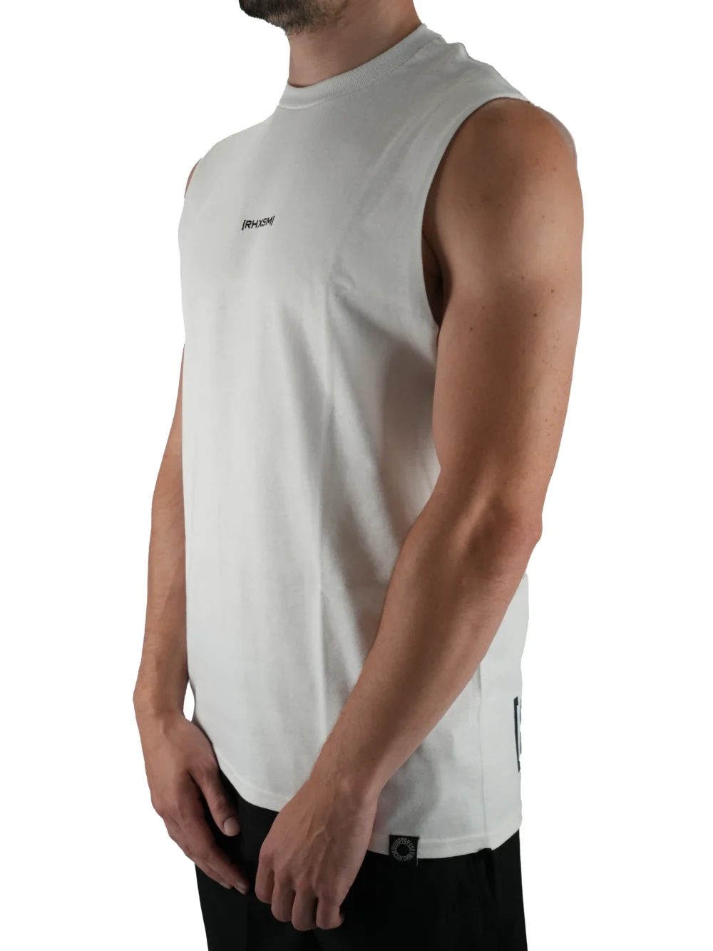 Model wearing the white oversized "[RHXSM]" tank (front view), showing the modern oversized fit of this essential workout gear.
