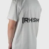Model wearing the white "[RHXSM]" tee (back view), showcasing the impactful back design and dropped shoulders from the calisthenics clothing brand RHSM.