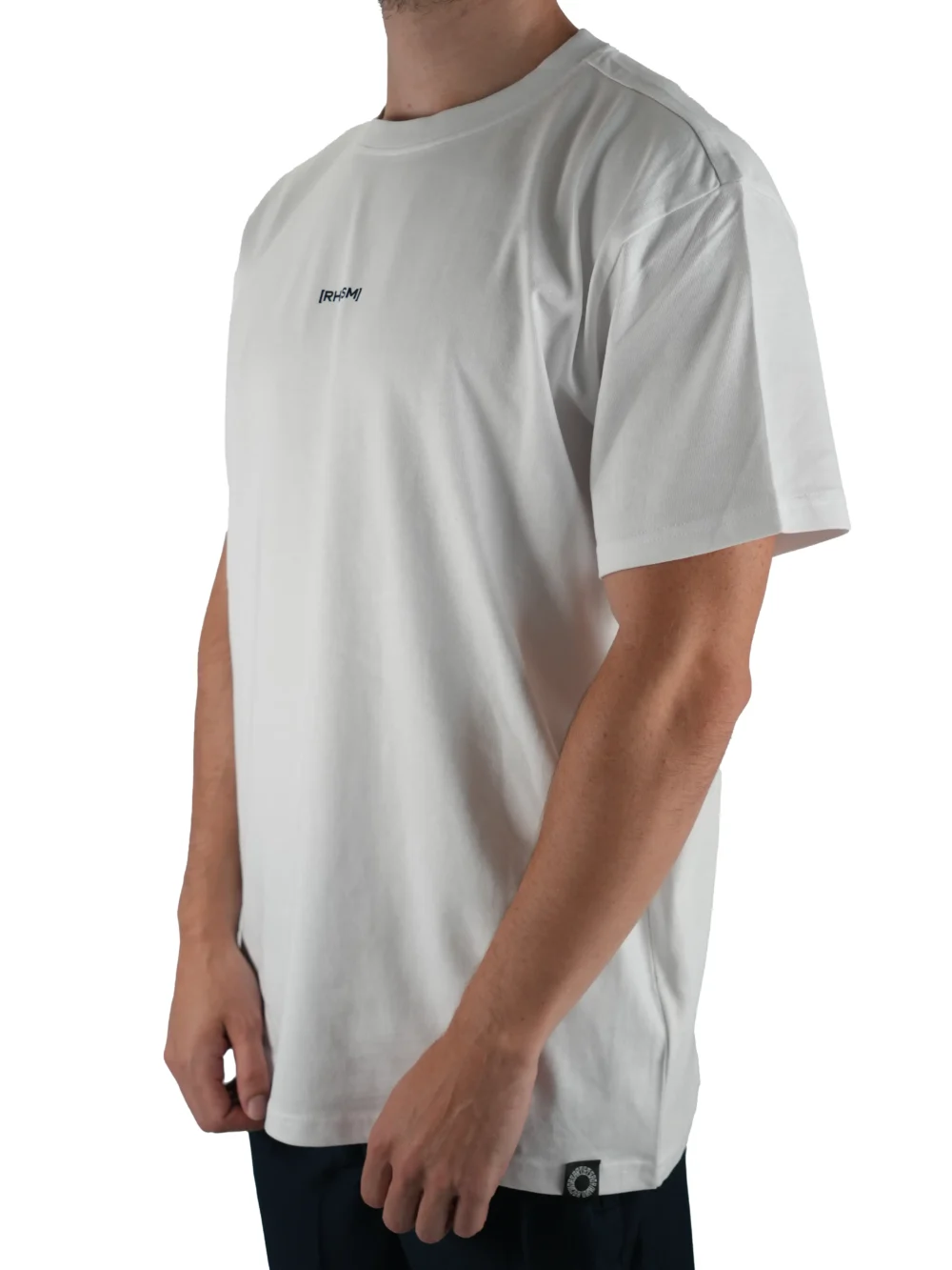 Model wearing the white oversized "[RHXSM]" tee (front view), showing the modern oversized fit of this essential workout gear.