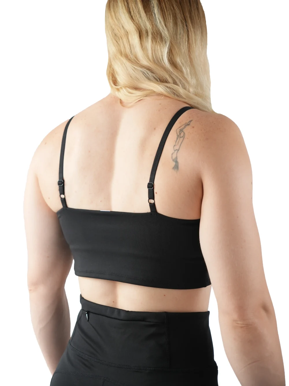Model showing the back strap design of the black sports bra, representing the minimalist line from the RHSM calisthenics clothing brand.