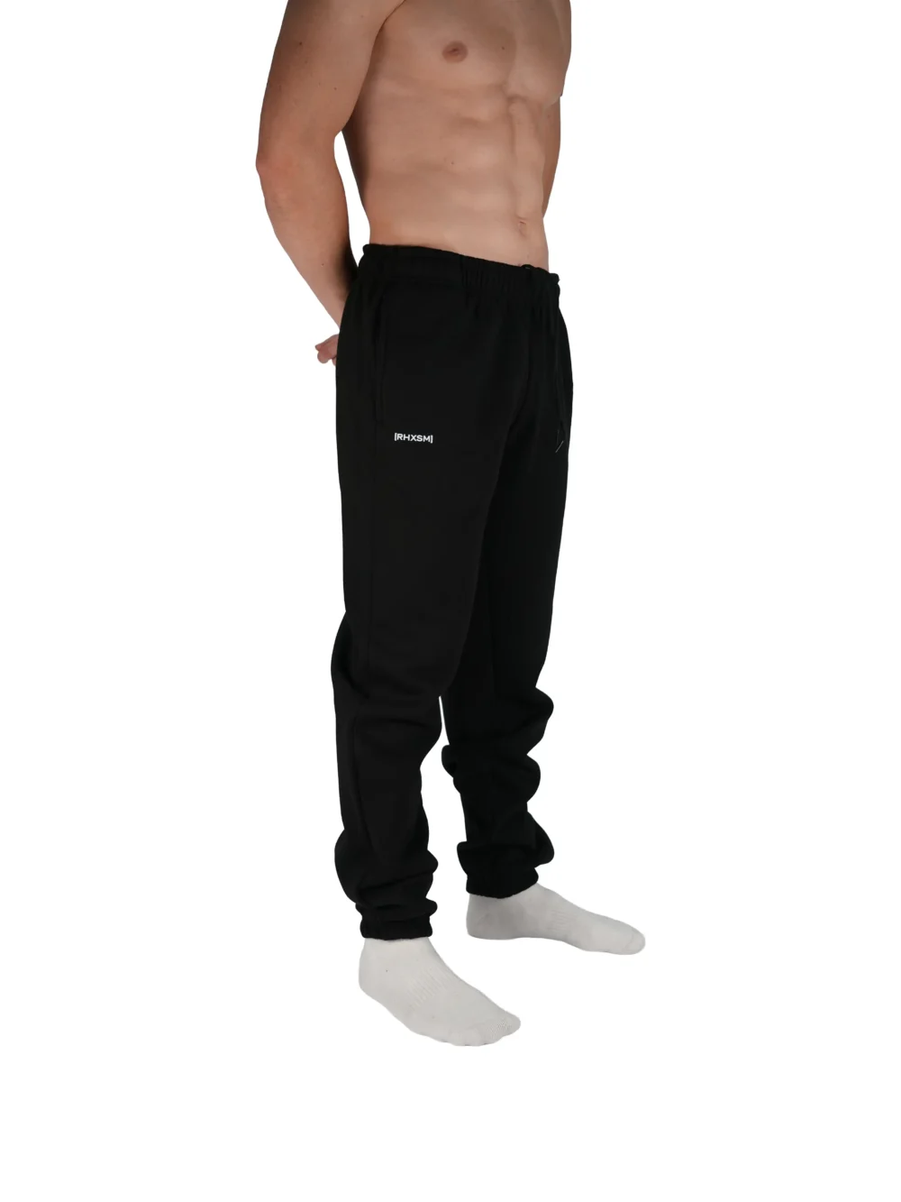 A close-up of the RHSM "[RHXSM]" sweatpants in black, detailing the subtle pocket graphic that defines this minimalist piece from the calisthenics clothing brand.
