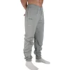 A close-up of the RHSM "[RHXSM]" sweatpants in grey, showing the small, subtle graphic on the right side pocket from the calisthenics clothing brand.
