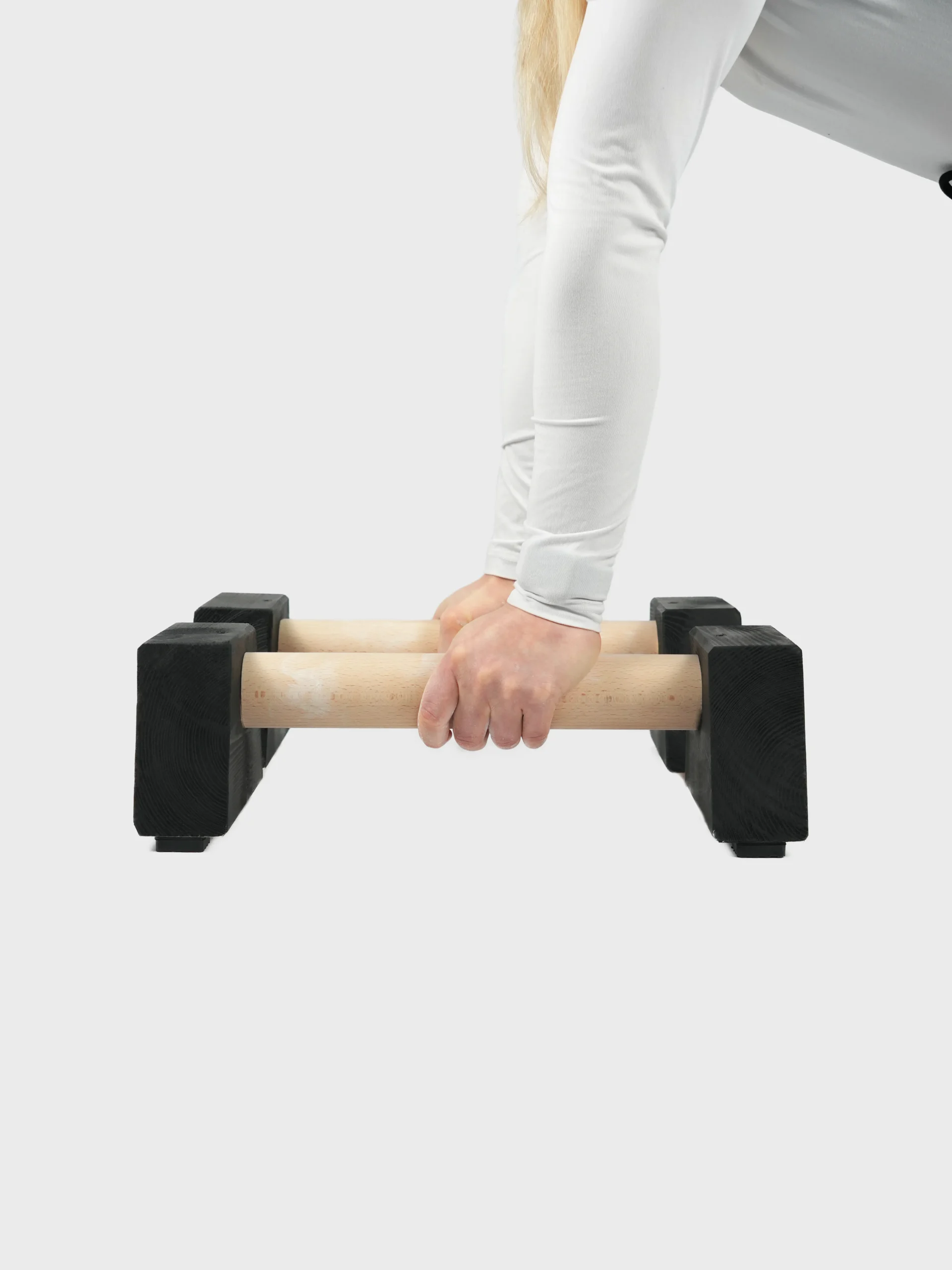 Athlete using RHSM Magnesium Chalk on wooden parallettes for a secure grip while wearing RHSM fitness apparel.